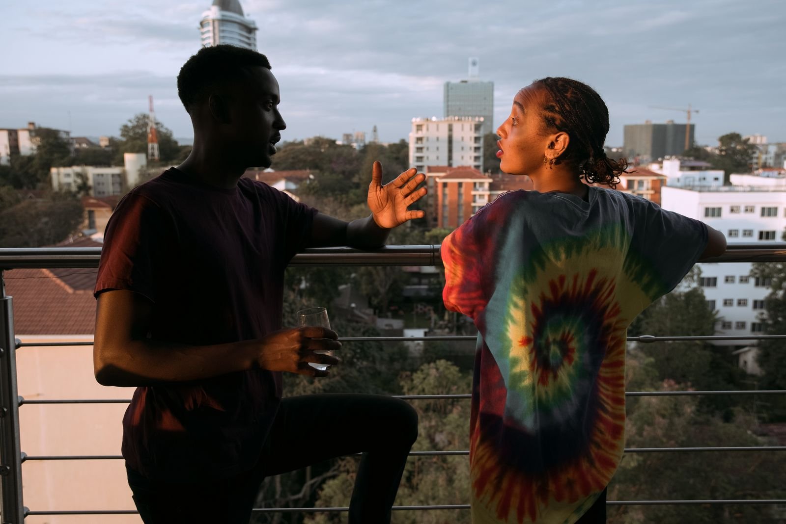 A young man and woman in conversation on a balcony overlooking Nairobi